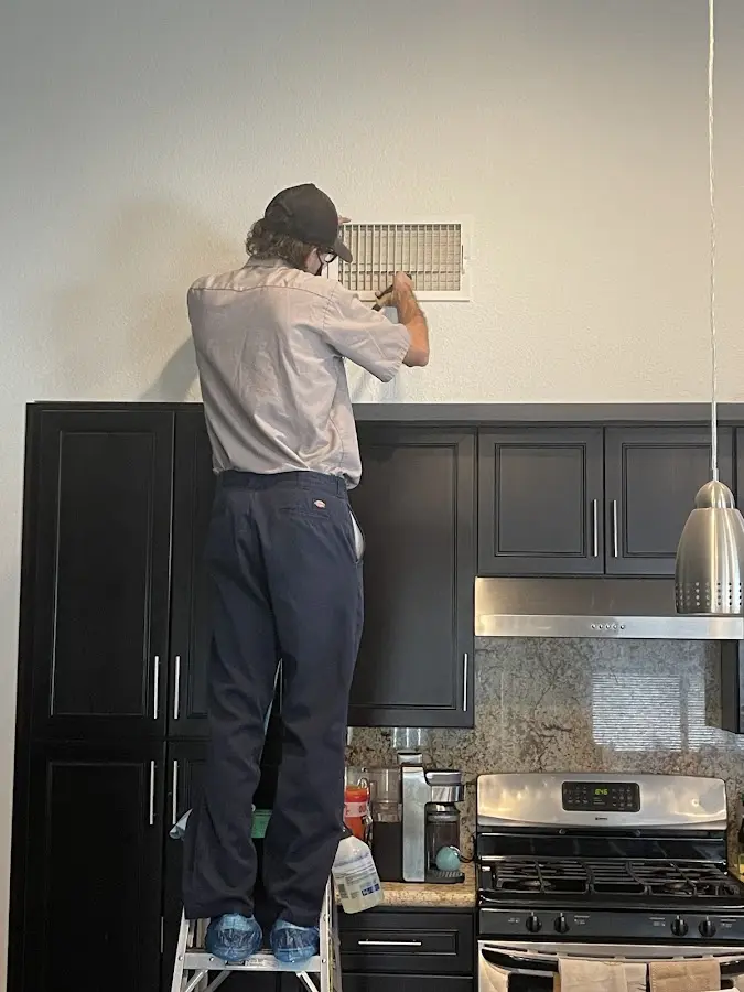 Technician inspecting an air vent during HVAC service in Washington